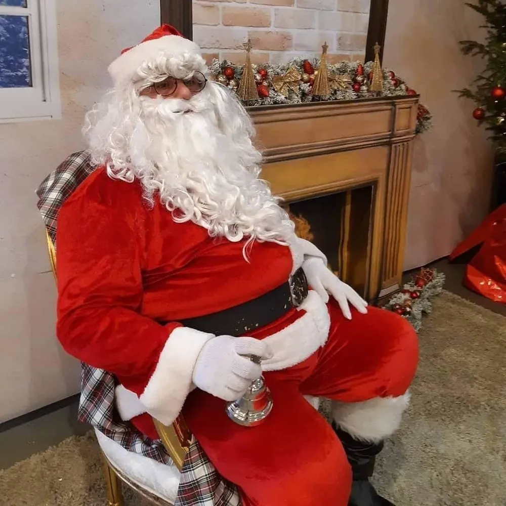Babbo Natale seduto accanto al camino con il campanello
