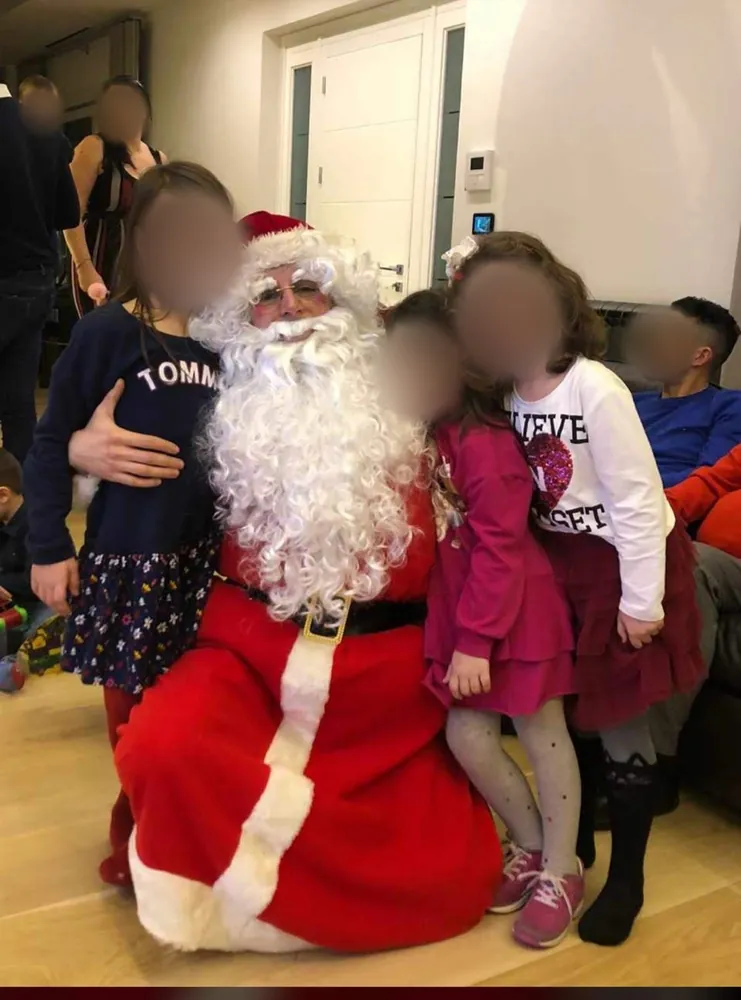 Babbo Natale seduto in salotto circondato dai bambini