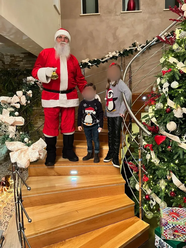 Babbo Natale con due bambini sulla scala accanto all'albero di Natale