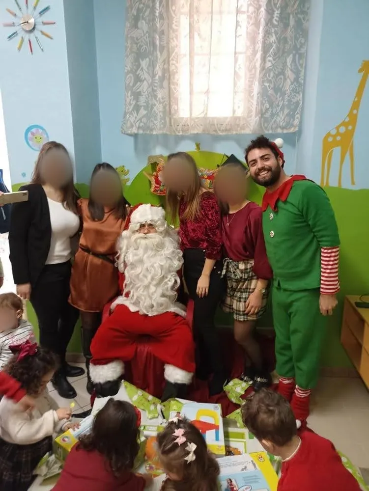 Babbo Natale ed elfo in una scuola dell'infanzia con le maestre e i bambini