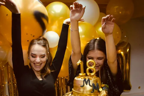 Due ragazze festeggiano i 18 anni con torta dorata e palloncini