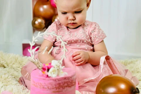 Bambina di 1 anno con torta rosa al suo primo compleanno