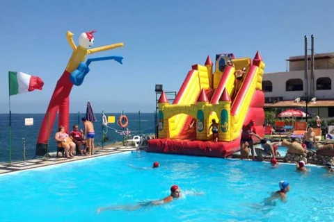 Scivolo gonfiabile gigante in piscina vista mare con bambini