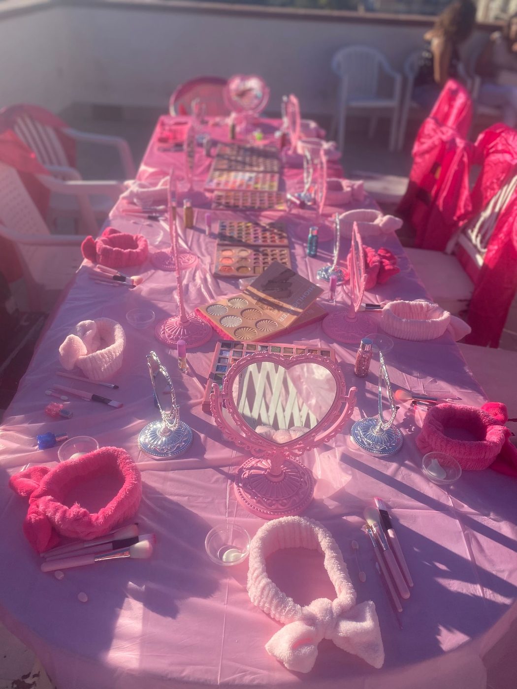 Tavolata Beauty Spa Party allestita con specchi cuore rosa, palette make-up e kit beauty per ogni bambina