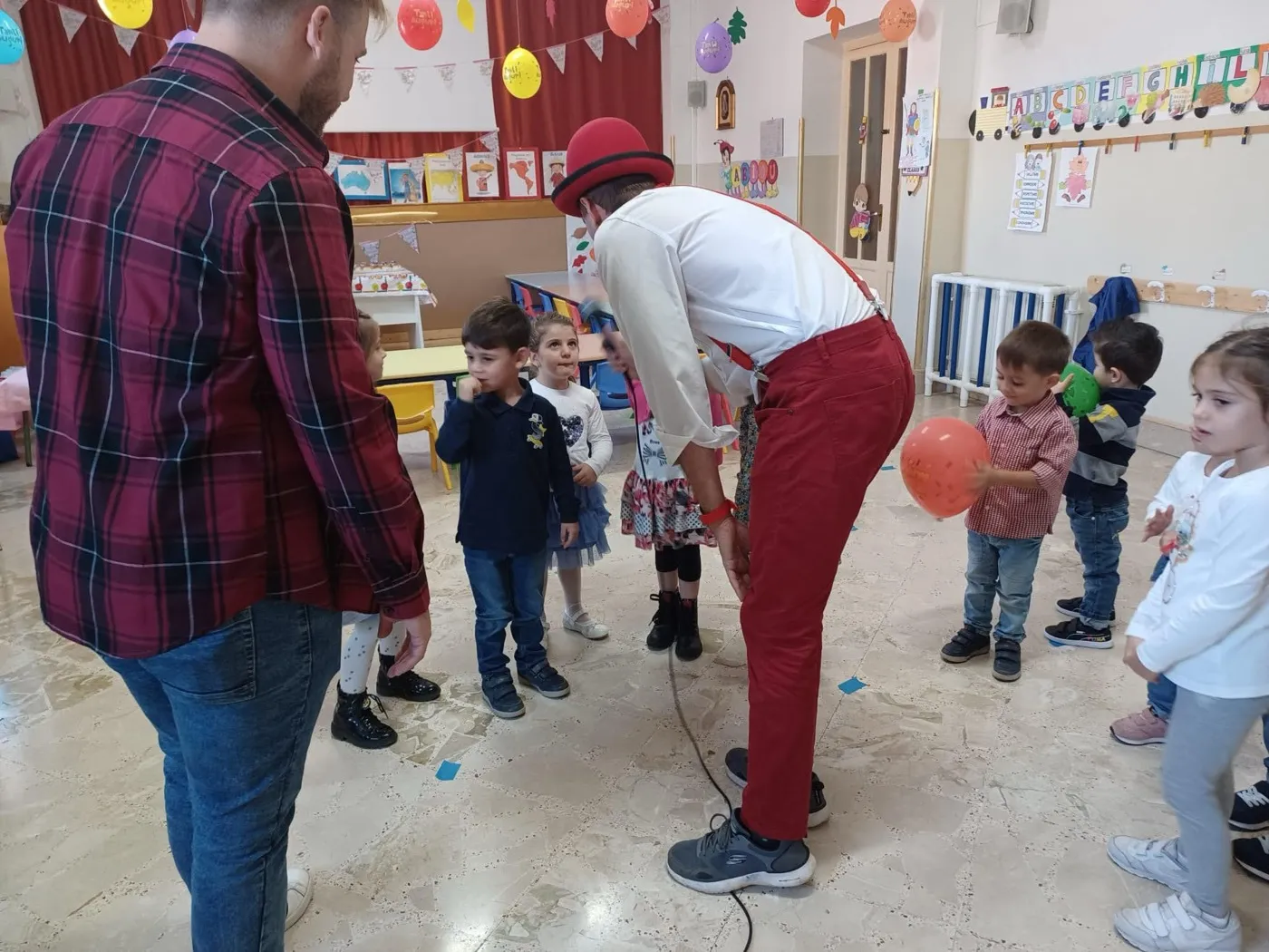 Animatore consegna palloncini ai bambini di una sezione della scuola materna