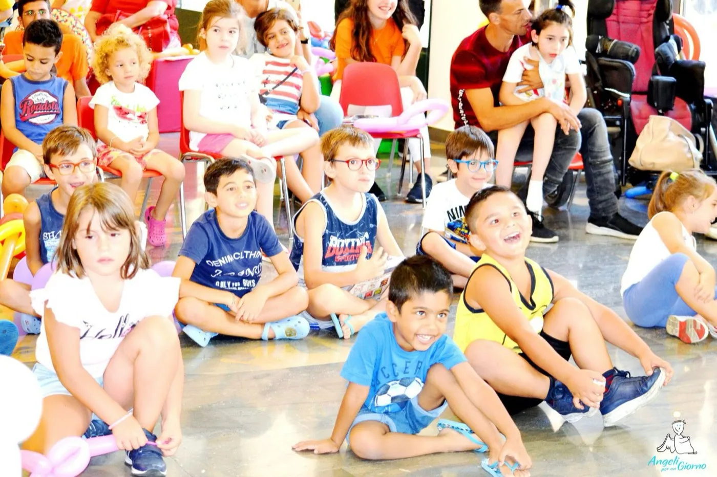 Bambini seduti in palestra che ridono durante uno spettacolo