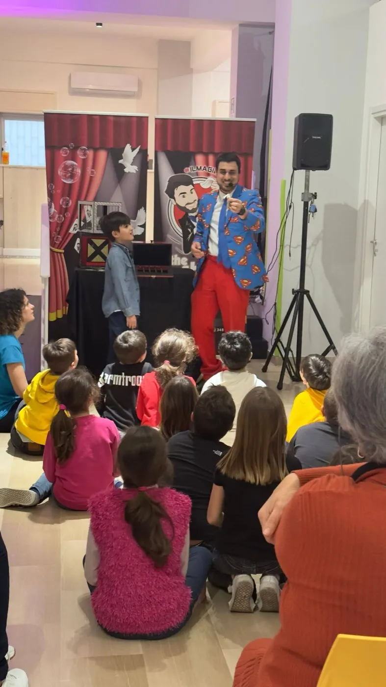 Un bambino sale accanto al mago come volontario davanti ai compagni