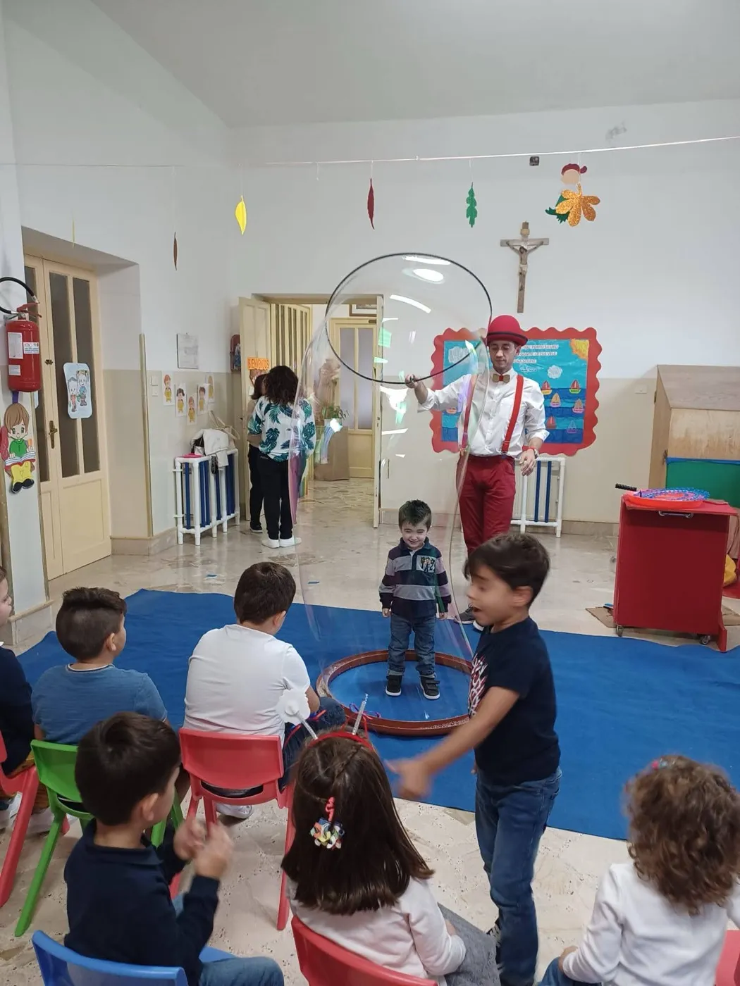 Bambino dentro una bolla di sapone gigante nel salone di una scuola dell'infanzia