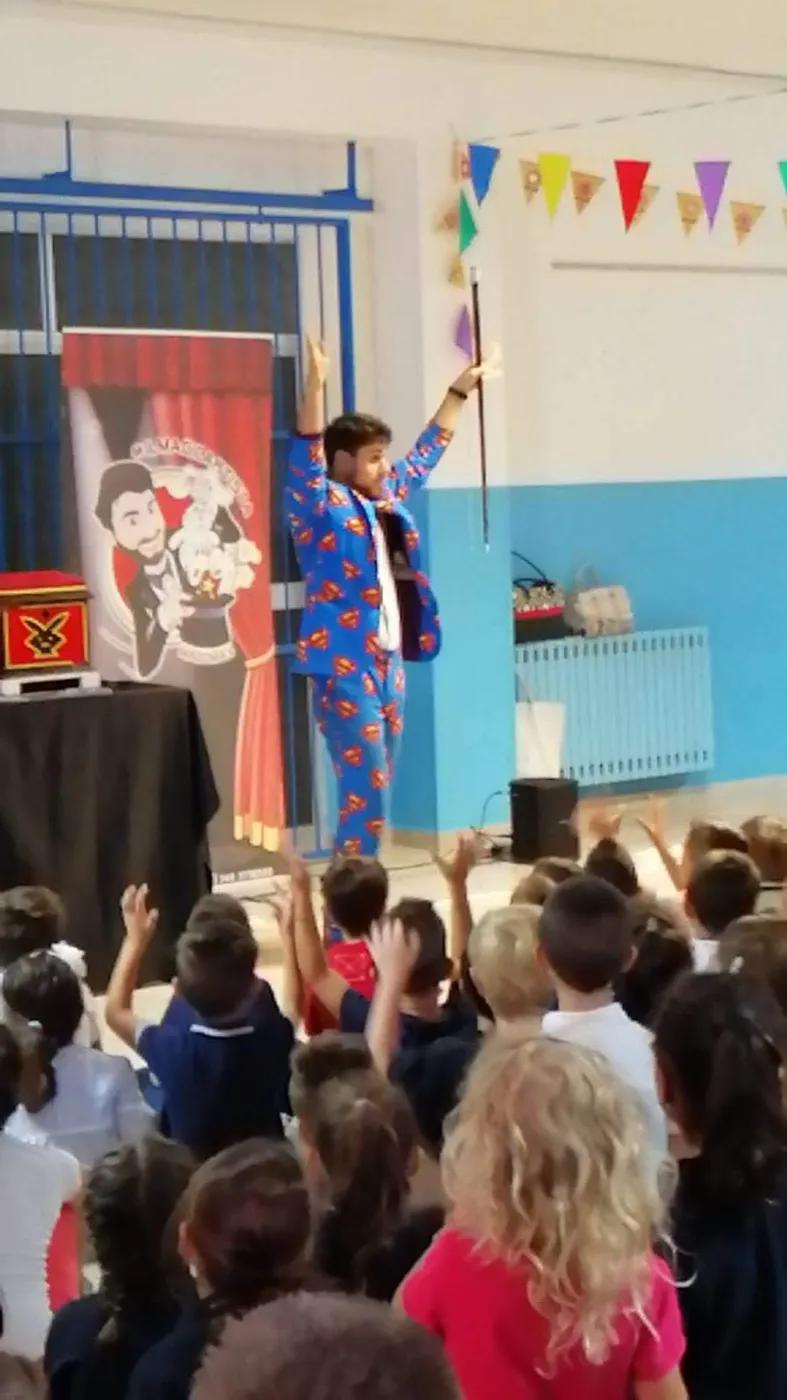 Bambini con le mani alzate durante lo show di magia nella palestra della scuola