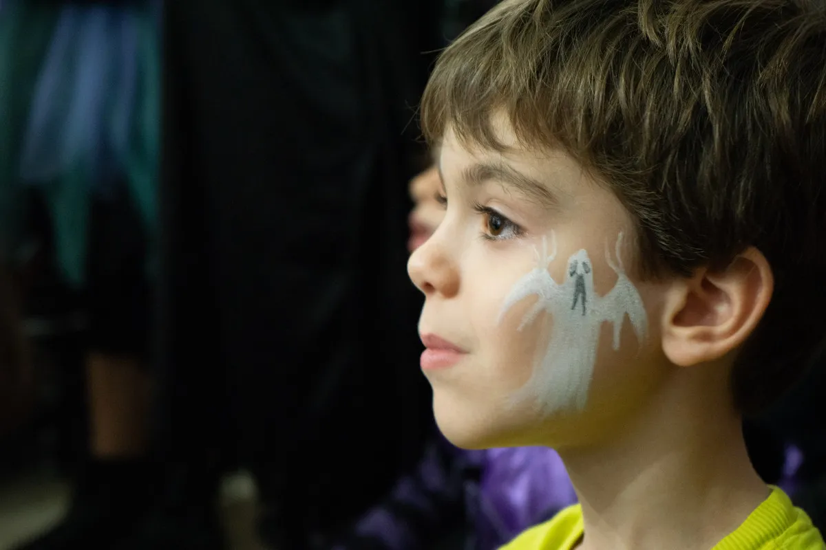 Bambino con trucco da fantasma segue incantato lo spettacolo