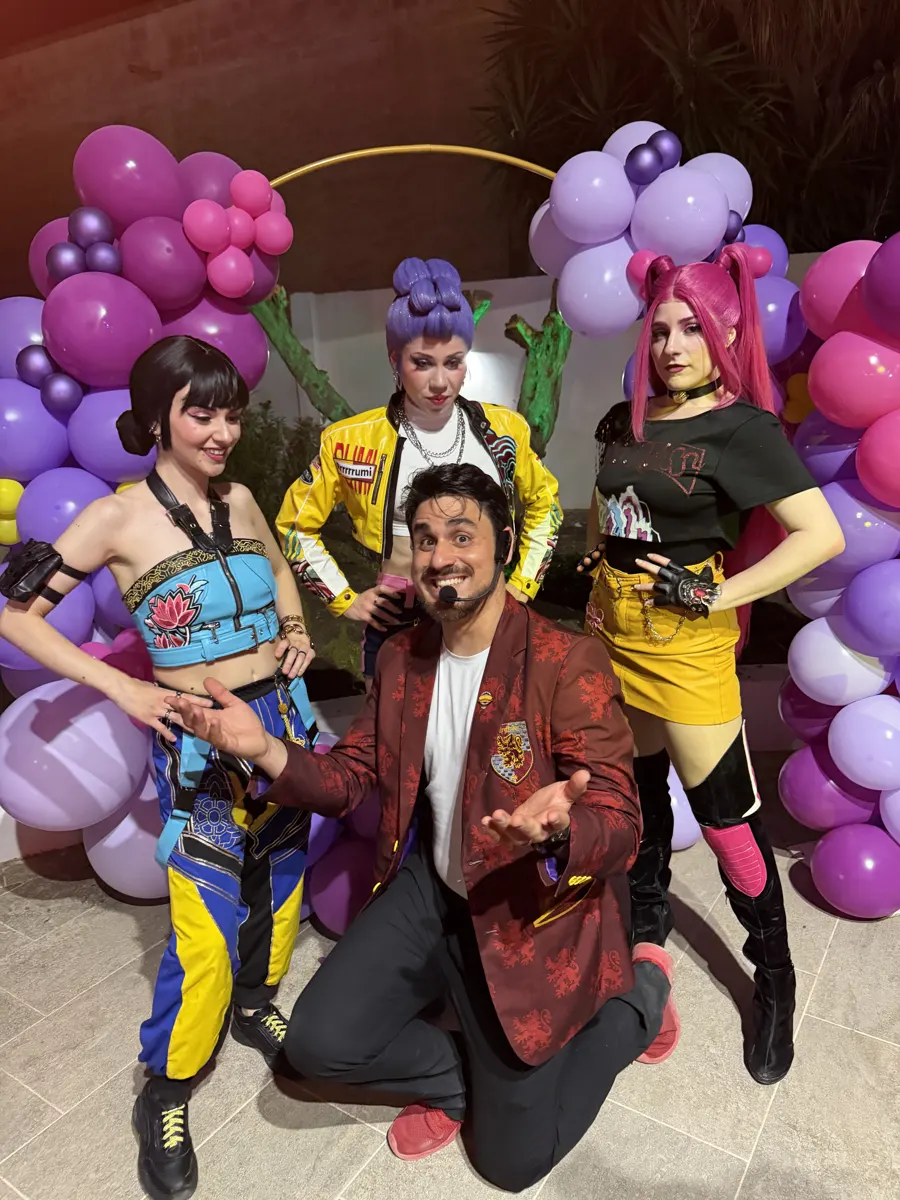 Performer Huntrix davanti all'arco di palloncini viola