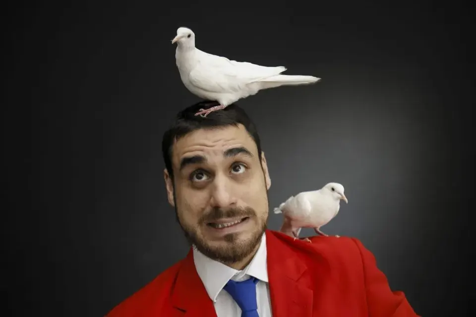 Il Mago Max in posa comica con le colombe durante il family show