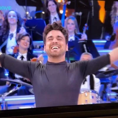 Il Mago Max sul palco di La Corrida 2025 su NOVE con le braccia aperte e sorridente durante lo show