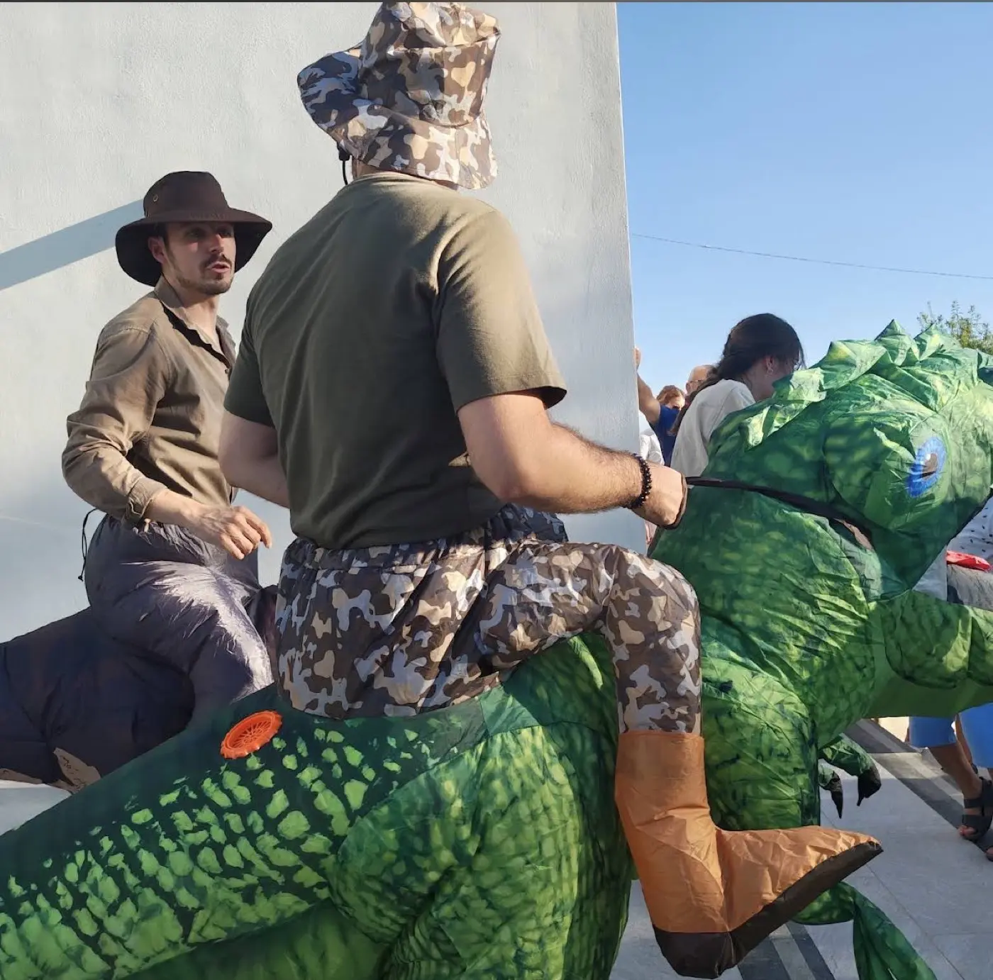 Animatori in costume esploratore e dinosauro verde cavalcabile alla festa Jurassic World