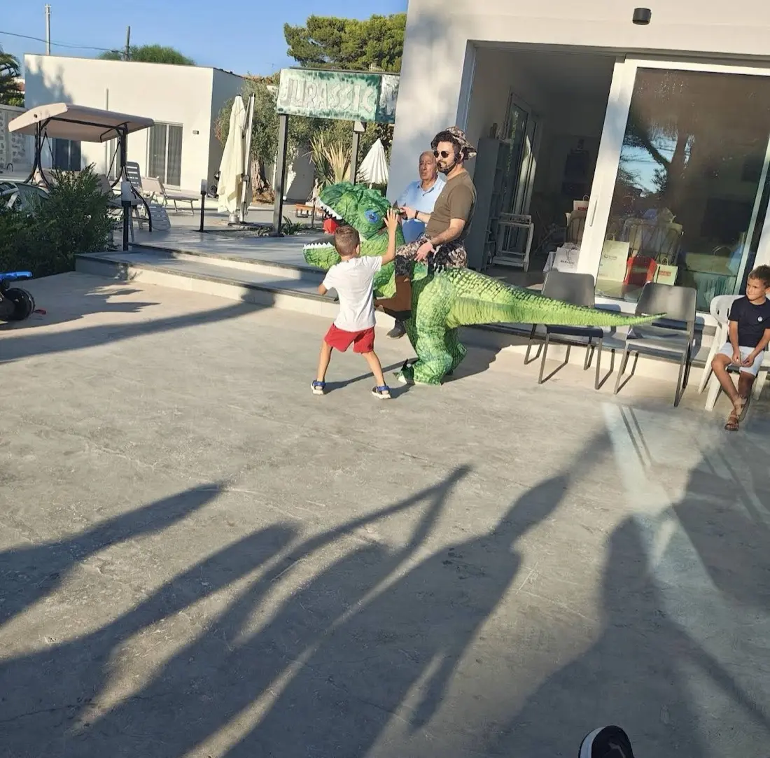 Bambino gioca con l'animatore sul dinosauro verde cavalcabile