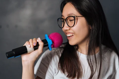 Donna sorridente canta al microfono in serata karaoke