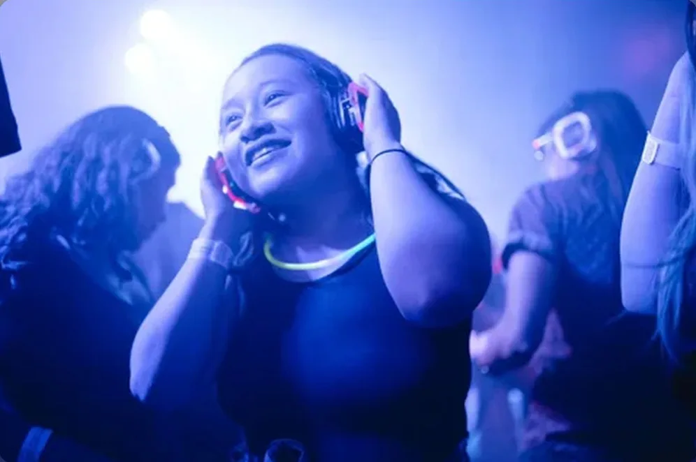 Ragazza che balla con le cuffie luminose della silent disco in una serata per adulti a Palermo