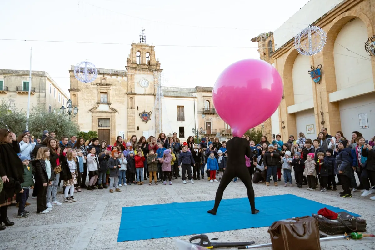 Il pallone gigante rimbalza sul pubblico in piazza durante lo spettacolo di clownerie