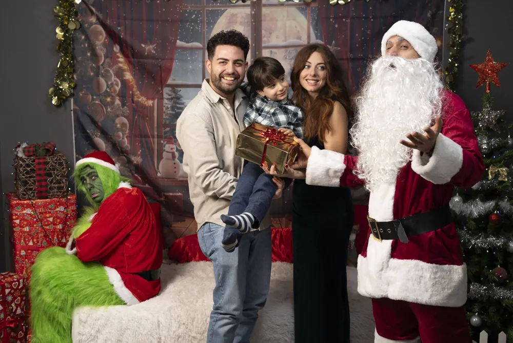 Famiglia in posa con Babbo Natale e il Grinch al set natalizio