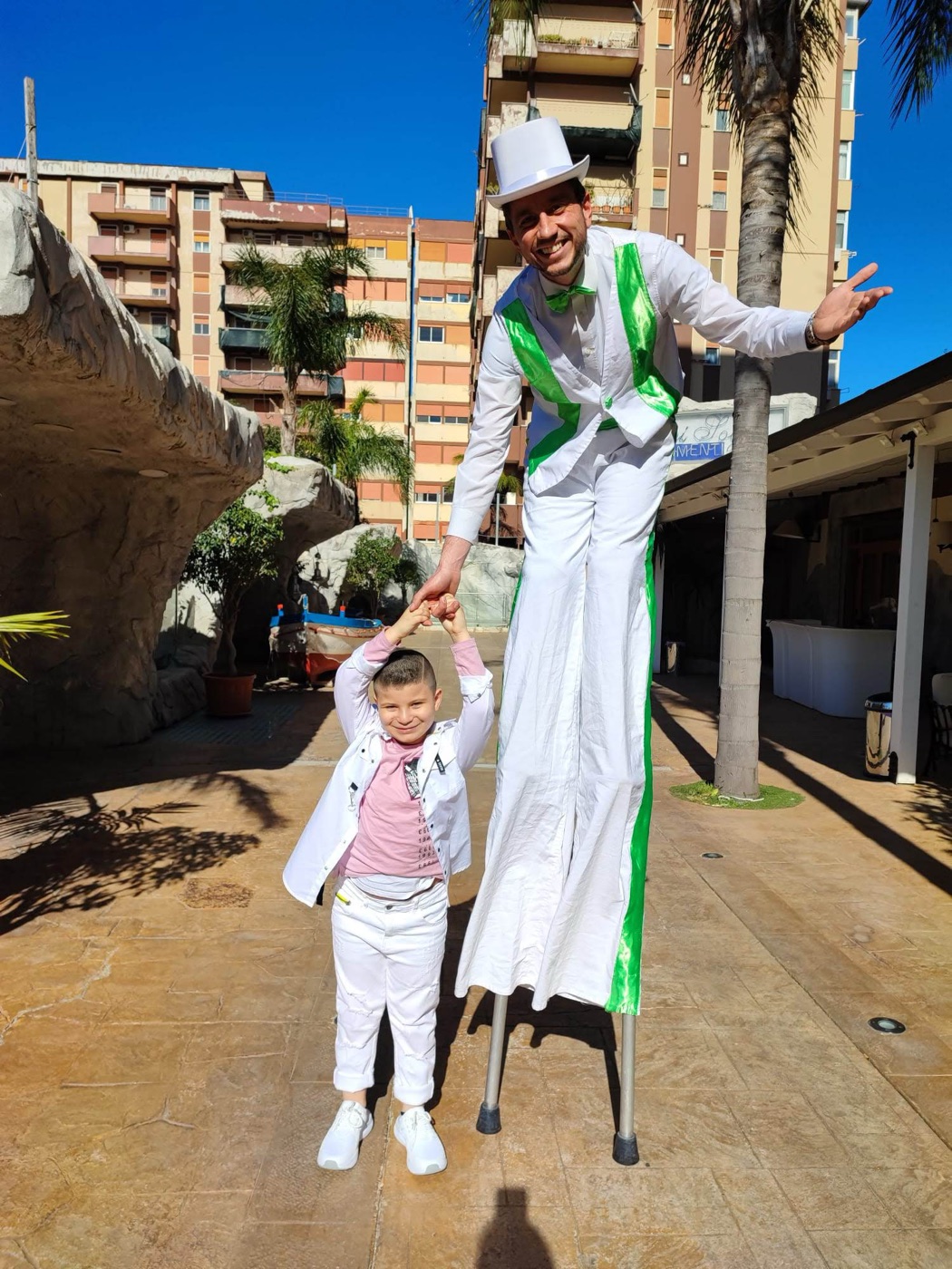 Trampoliere in costume bianco e verde che gioca con bambino durante festa privata estiva