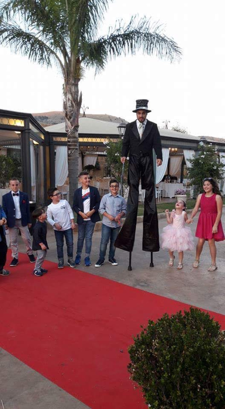 Trampoliere elegante in frac nero e cilindro durante matrimonio con bambini su tappeto rosso