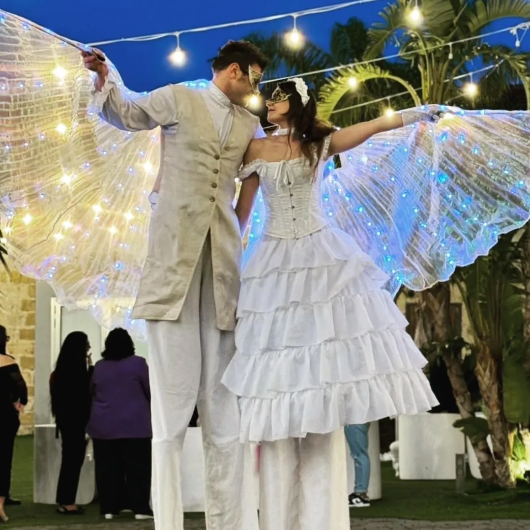 Coppia di trampolieri con ali luminose colorate in spettacolo serale